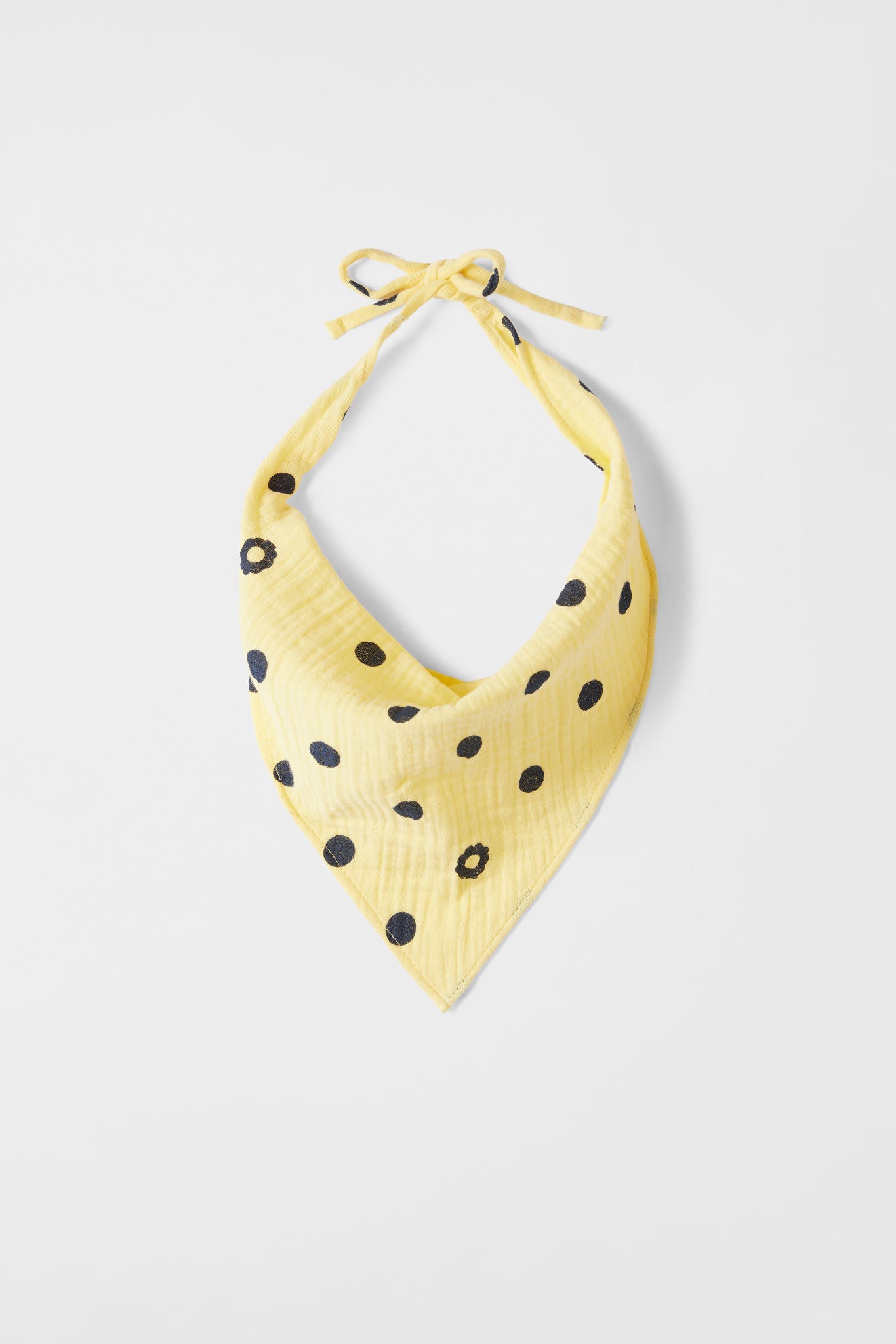 Yellow bandana with black polka dots on a light gray background